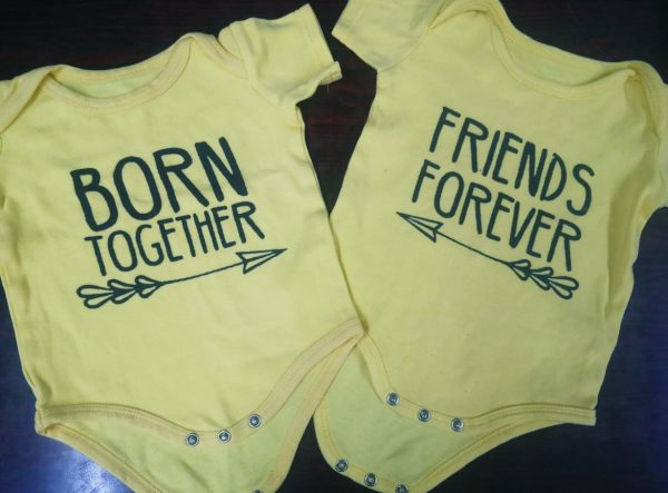 Zwei gelbe Baby-Bodies: Einer mit der Aufschrift "Born together", der andere mit "Friends forever".